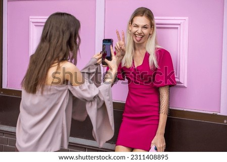 Two young girlfriends are photographed on a mobile phone
