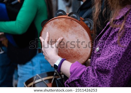 Santiago de Compostela, Spain; may 6 th 2023: young woman playing the tambourine on a foliade Royalty-Free Stock Photo #2311426253