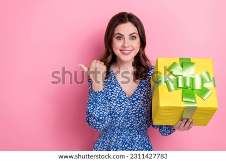 Photo of impressed woman wavy hairdo wear blue dress hold present box directing at shopping empty space isolated on pink color background