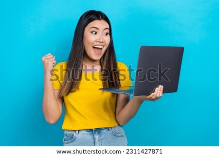Photo of young overjoyed crazy chinese woman playing gambling big lottery winning fist up hooray isolated on blue color background