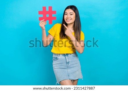 Photo of chinese woman wear yellow t-shirt mini skirt direct finger trend symbol pin hashtag promo isolated on blue color background