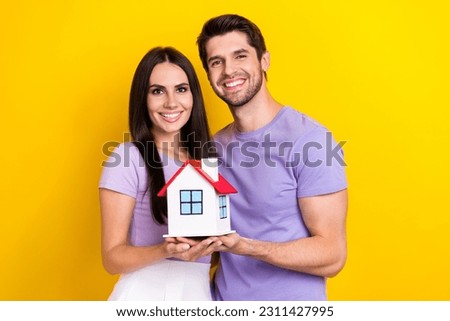 Photo portrait of attractive young woman man hold little house real estate wear trendy purple outfit isolated on yellow color background