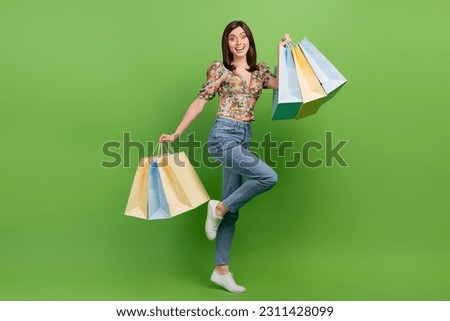 Full length portrait of cheerful lovely person hands hold boutique bags isolated on green color background