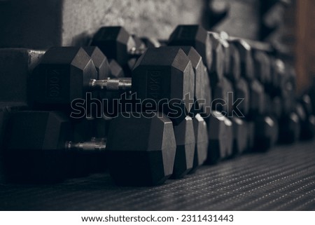Dumbbell, empty gym and metal for exercise on floor for power, sport or abstract background. Fitness, workout and training with iron weights for bodybuilding, health or wellness club membership Royalty-Free Stock Photo #2311431443