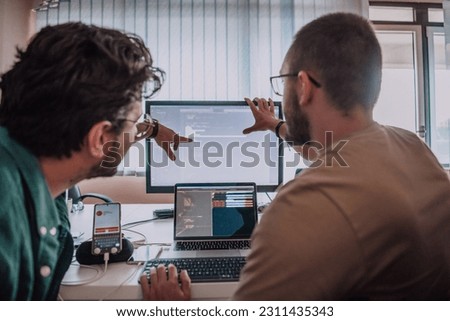 Programmers engrossed in deep collaboration, diligently working together to solve complex problems and develop innovative mobile applications with seamless functionality. Royalty-Free Stock Photo #2311435343