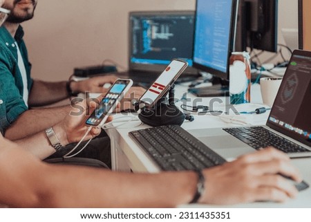 Programmers engrossed in deep collaboration, diligently working together to solve complex problems and develop innovative mobile applications with seamless functionality. Royalty-Free Stock Photo #2311435351