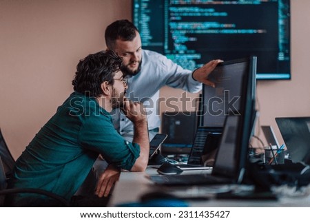 Programmers engrossed in deep collaboration, diligently working together to solve complex problems and develop innovative mobile applications with seamless functionality. Royalty-Free Stock Photo #2311435427