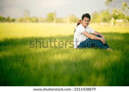 Asian man sitting and relaxing among green fields