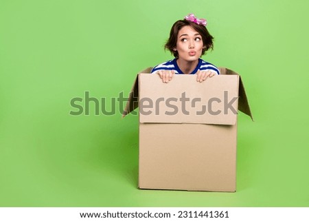 Full body photo of young girl pouted lips surprise look empty space anticipations inside carton box isolated on green color background