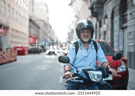 adult man on a moped in the city Royalty-Free Stock Photo #2311444925