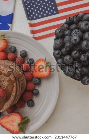 Pancakes with forest fruits berries on beautiful table. Healthy breakfast. Blueberries, raspberries and strawberry on pancakes. Independence Day 4th of July. 