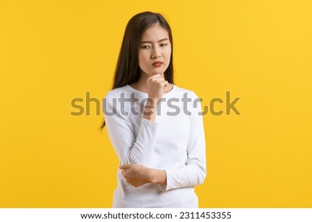 Cute asian young woman in white casual dress looking up and thinking  imagination isolated on yellow background in studio.banner size.