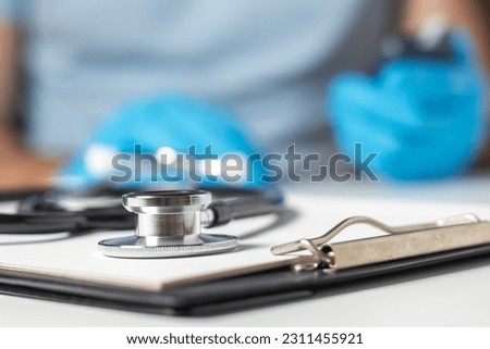 Stethoscope and pen laying on patient information blank on doctor background.