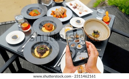 Closeup shot of a female blogger hands capturing and record video of lunch using a smartphone in a tropical restaurant.