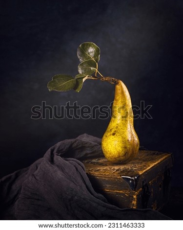 Rural still life, low key dark photography - view of a lone pear fruit on a wooden chest, closeup with selective focus