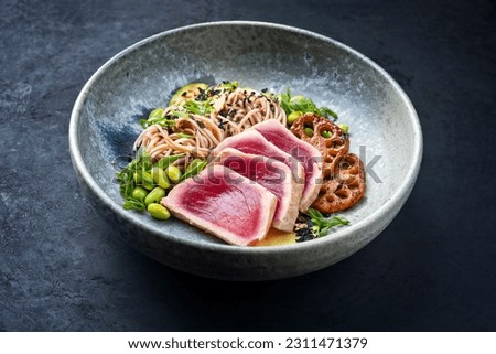 Modern style traditional Japanese gourmet seared tuna fish steak tataki with soba noodles and stir-fried vegetables served as close-up on a Nordic design plate with copy space Royalty-Free Stock Photo #2311471379