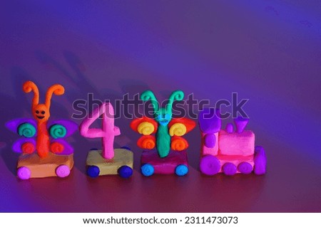 Toy train made of plasticine with butterflies and the number 4. Birthday. A festive event. Color background.