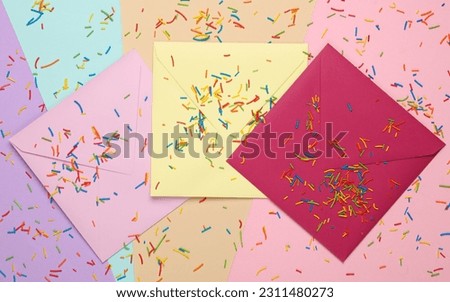 Colored envelopes with sprinkles for cake on pastel background