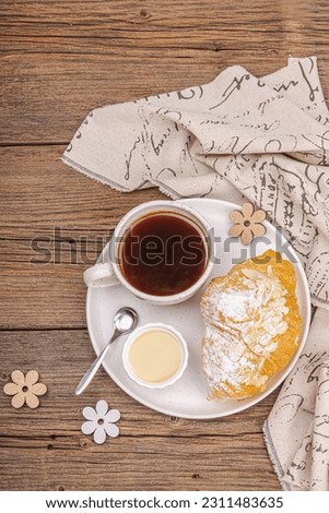 Good morning concept. Breakfast with cup of coffee and fresh croissant. Sweet creamy sauce, wooden background, top view