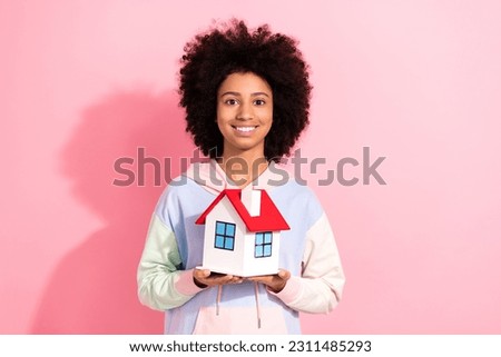 Photo of cheerful pretty little child dressed hoodie smiling holding small house isolated pink color background