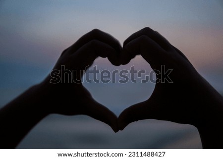  Hands making a heart shape at sunset