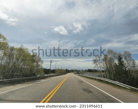 An open highway under a cloudy sky running across a bridge.