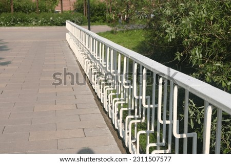 Pedestrian bridge with white railings on the road in the Yuzhnoye Butovo landscape park, Bridge in the summer park. Moscow, June 2023 Royalty-Free Stock Photo #2311507577