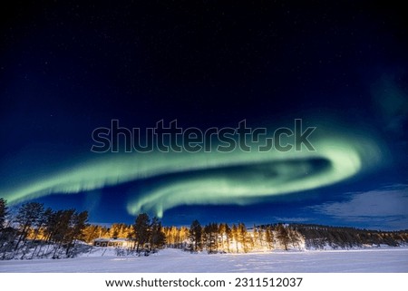 Circular green Northern lights (aurora borealis) 
above Ounasjärvi lake in Hetta, Lapland, Finland
