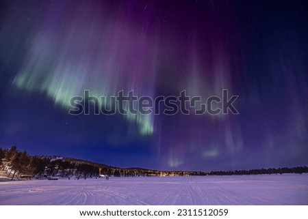 Purple, blue, white and green Northern lights (aurora borealis) 
above Ounasjärvi lake in Hetta, Lapland, Finland Royalty-Free Stock Photo #2311512059