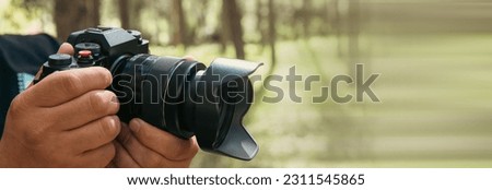 photographer holds a camera in his hand in the forest
