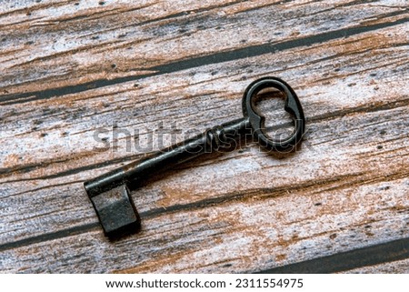 Old iron key photographed in a wooden background.