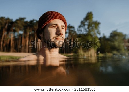 Portrait of young man soaks in the winter lake at morning. Male person taking care of his heath Royalty-Free Stock Photo #2311581385