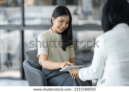 Confident young asian woman learning business online through tablet with successful professional in finance and management while sitting on couch at office.