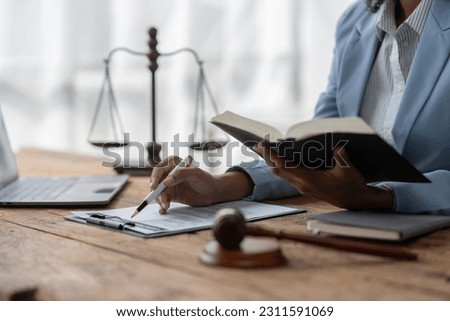 American woman lawyer or businesswoman African working with laptop, searching, analyzing data, reading contract documents work with law books hammer of justice Consulting lawyer concept. Royalty-Free Stock Photo #2311591069