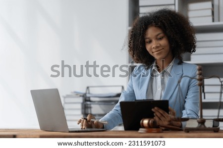 American woman lawyer or businesswoman African working with laptop searching for information, reading codes, documents, studying constitution to protect rights work with law books hammer of justice.