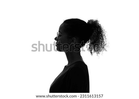 Profile silhouette of thinking black woman in studio shot. Royalty-Free Stock Photo #2311613157