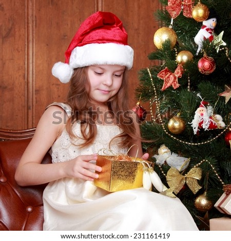 Little girl wearing Santa Claus red hat with Christmas presents