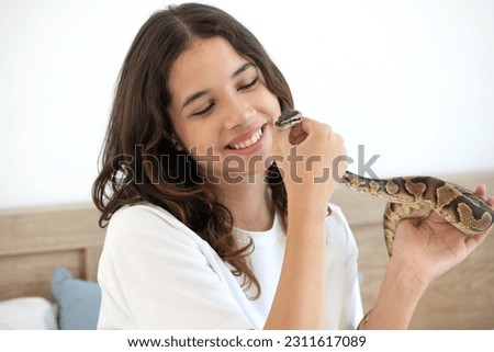 Teen girl with her snake exotic pet, Ball Python, smiling girl holding Royal python in her hands at home