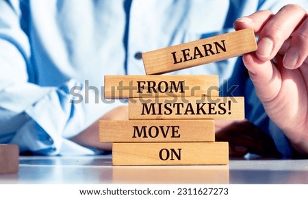 Close up on businessman holding a wooden block with a "Learn from mistakes. Move on" message Royalty-Free Stock Photo #2311627273