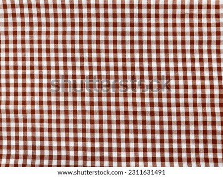 Red or Maroon colored fabric or textile or cloth with square pattern or checkered pattern