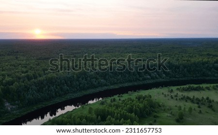 Beautiful river among the woods. Drone aerial view. Sunset time picture.