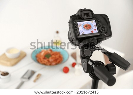 Professional camera with picture of spaghetti on display in studio, space for text. Food stylist