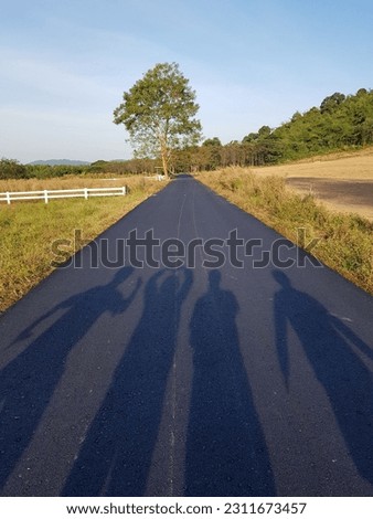 Take a picture of the silhouette of a person backlit. On a country road in the morning