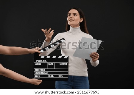 Actress performing while second assistant camera holding clapperboard on black background. Film industry Royalty-Free Stock Photo #2311679695