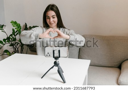 Happy young girl recording a vlog, streaming online for followers indoors on the sofa Royalty-Free Stock Photo #2311687793