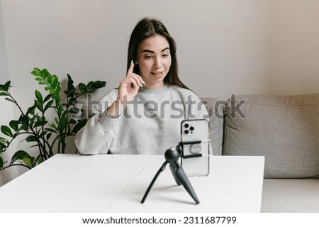 Happy young girl recording a vlog, streaming online for followers indoors on the sofa Royalty-Free Stock Photo #2311687799
