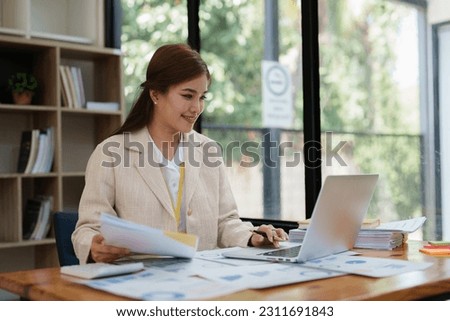 Asian Business person makes analysis and research financial report at office, analyzes profits. Accountant checks status of financial Royalty-Free Stock Photo #2311691843