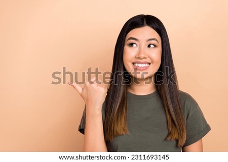 Photo portrait of charming wondered asian girl direct thumb finger empty space mockup isolated beige pastel color background