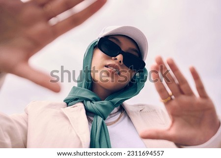 Low angle portrait, woman and city for muslim fashion with gen z aesthetic, streetwear and sky background. Young islamic girl, student and clothes with sunglasses, freedom and outdoor travel in Dubai Royalty-Free Stock Photo #2311694557