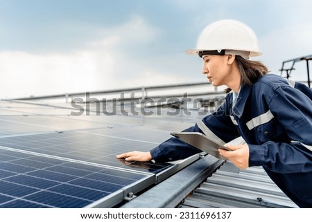 Woman engineer electrician using a hand to check solar panels on the roof, clean energy power nature, photovoltaic systems, the energy produced by the sun, sustainable business concept.  Royalty-Free Stock Photo #2311696137